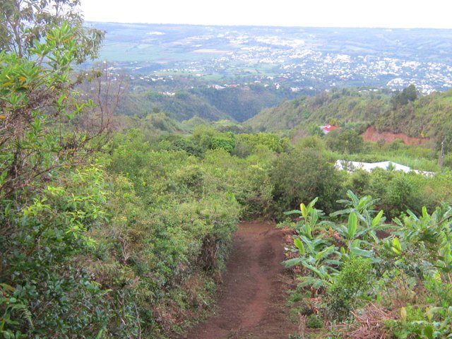 Début de la montée sur un terrain rouge et glissant avec vue sur mer