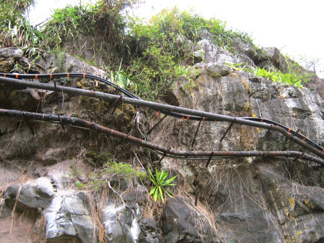 Des tuyauteries de tous âges et de tous types courent le long de la falaise
